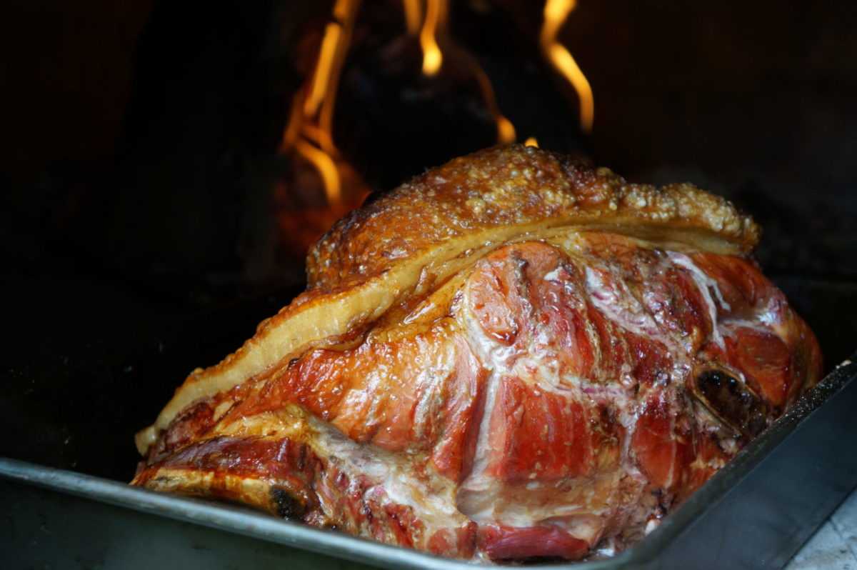 Pork shoulder cooking in wood fired oven
